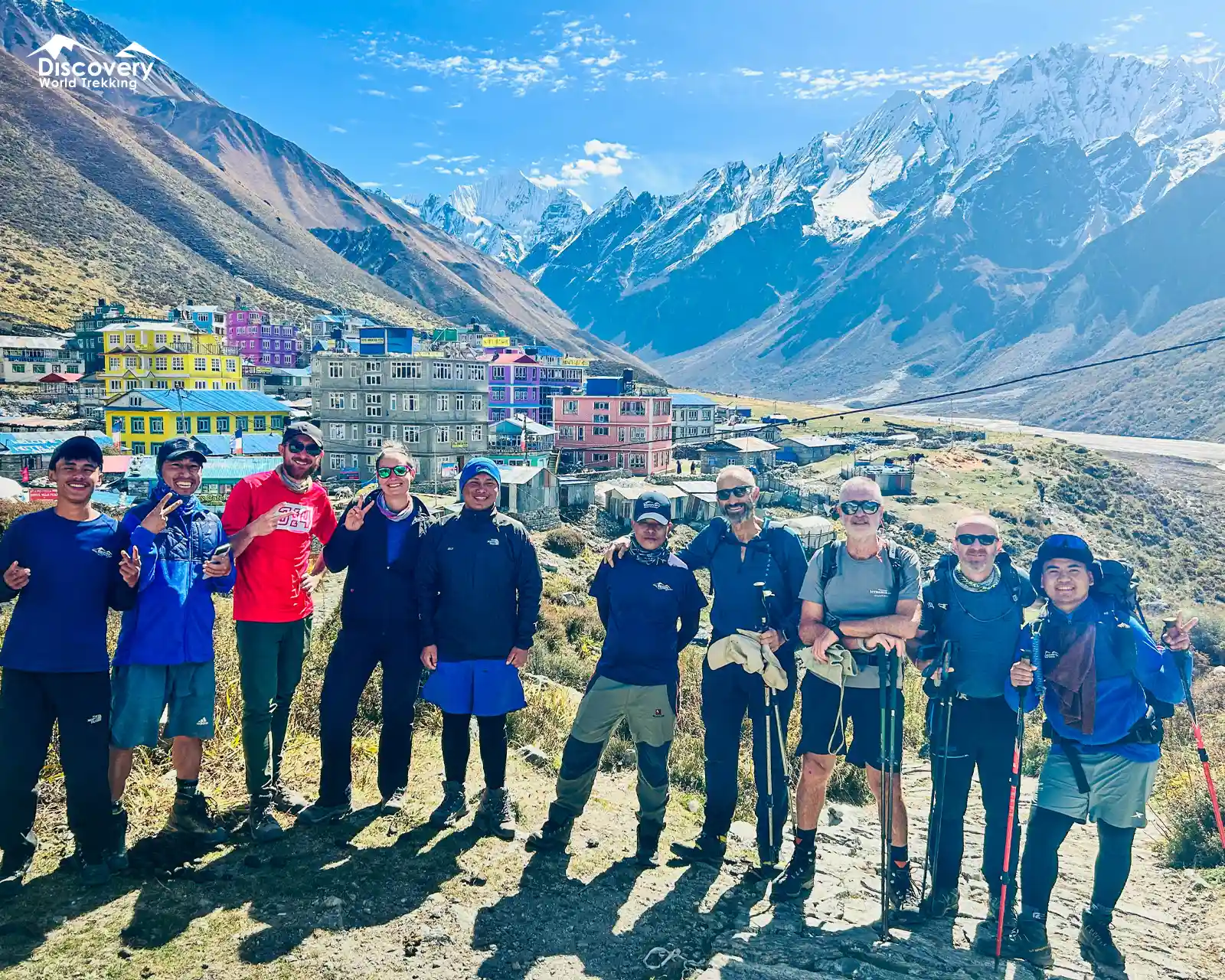 Posing during the Gosainkunda Lake Trek, with colorful houses below towering snow-covered peaks.