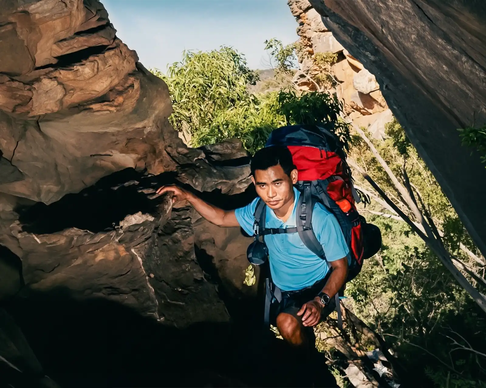 Climbing through a narrow rocky passage while trekking.